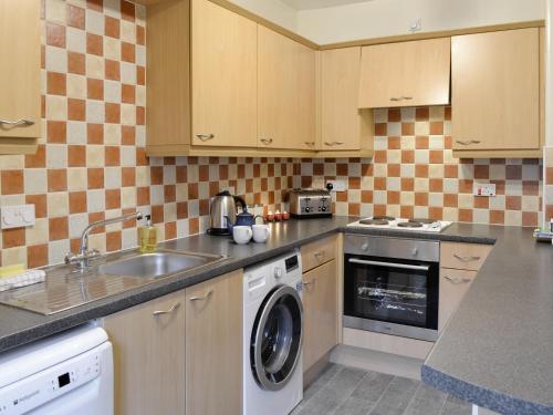 a kitchen with a sink and a washing machine at Baldowrie Farm Cottage in Ardler