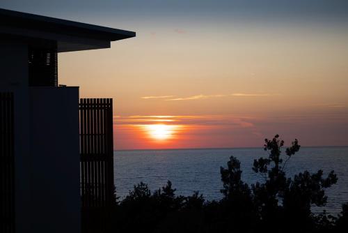 a sunset over the ocean with a building at PINEA Resort in Pobierowo