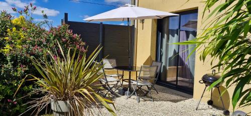 a patio with a table and an umbrella and some plants at Espace Acu-Nature in Saint-Évarzec