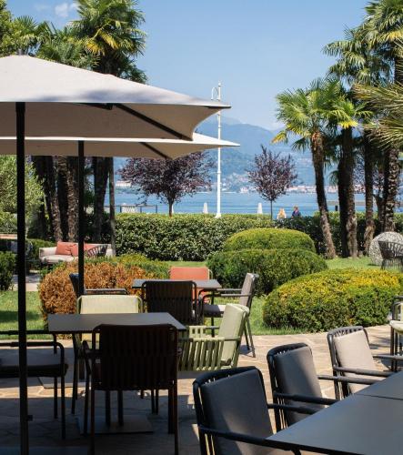 an outdoor cafe with chairs and tables and an umbrella at Hotel La Palma in Stresa