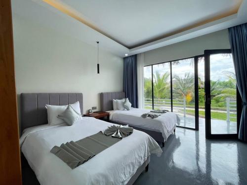 Phum Kompong SâmrongにあるPalmTown Boutique & Suitesのベッドが2つと大きな窓がある寝室