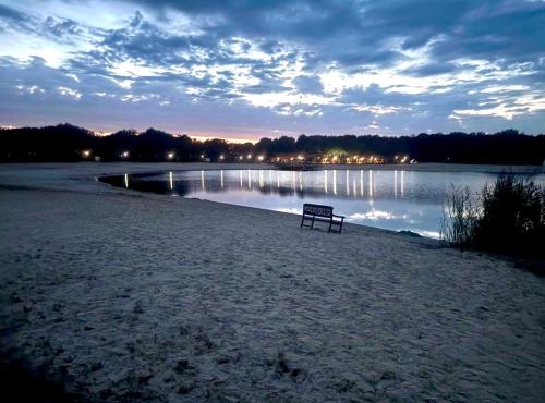 a bench sitting on the beach near a body of water at Ermwood Cottage in Erm
