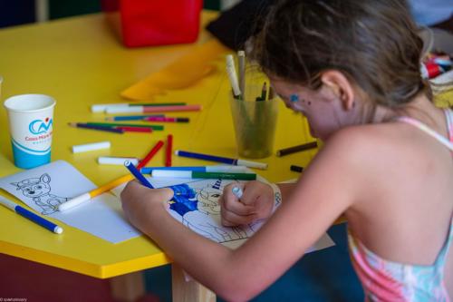 a young girl working on a drawing on a table at Casa Mare Resort - ex, Royal Tulip Beach Resort in Port Ghalib