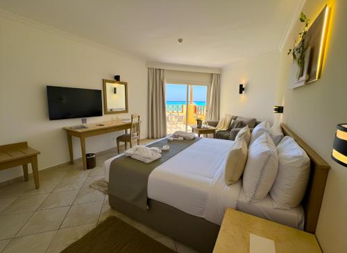 a hotel room with a large bed and a television at Casa Mare Resort - ex, Royal Tulip Beach Resort in Port Ghalib