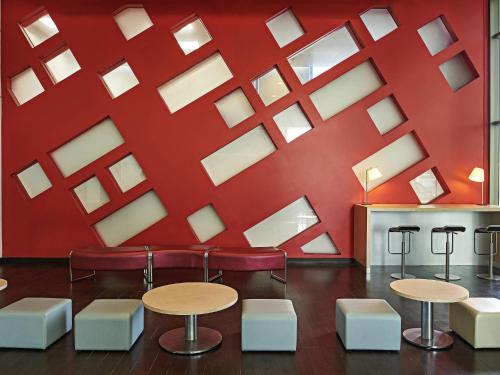 a red wall with tables and chairs in a room at Ibis Cancun Centro in Cancún