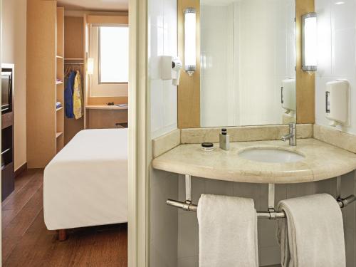 a bathroom with a sink and a bed in a room at Ibis Cancun Centro in Cancún