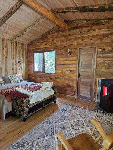 a bedroom with a bed in a log cabin at Cabaña Refugio Cascada in Llanada Grande