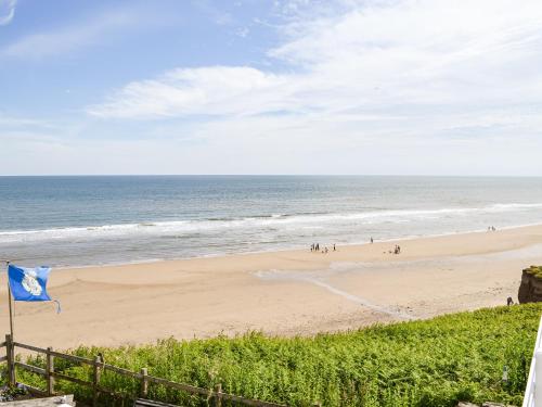 a beach with a blue flag and people on it at The Chalet - Uk34712 in Reighton