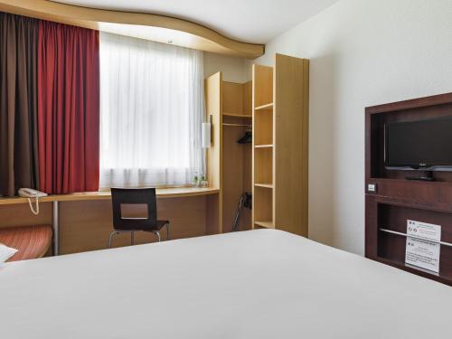 a hotel room with a bed and a television at ibis Warszawa West Station in Warsaw