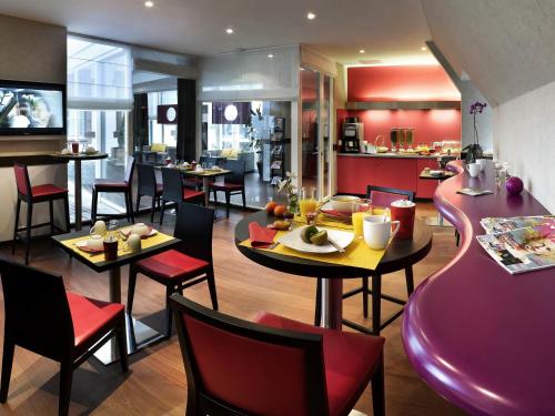 a restaurant with tables and chairs and a kitchen at Aparthotel Adagio Strasbourg Place Kleber in Strasbourg