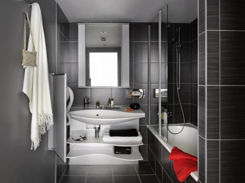 a bathroom with a white sink and a shower at Aparthotel Adagio Strasbourg Place Kleber in Strasbourg