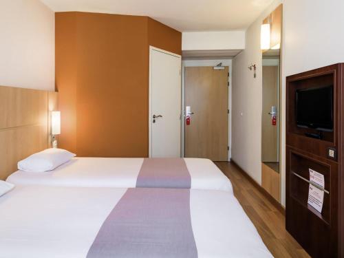 a bedroom with a large bed and a flat screen tv at ibis Warszawa West Station in Warsaw