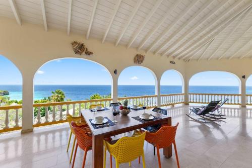 ein Esszimmer mit Tisch und Stühlen und dem Meer in der Unterkunft Villa Barbulete - Exclusive luxury sea view villa at Cas Abou in Dorp Soto