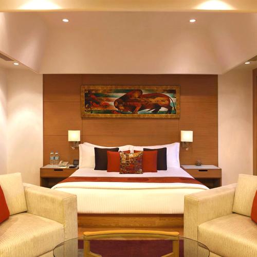 a bedroom with a large bed and two chairs at Hotel Ambs Plaza IGI Airport in New Delhi