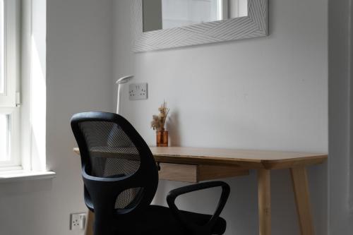 a black chair sitting in front of a wooden desk at Holyrood Duplex 3-Bedroom Apartment in Edinburgh