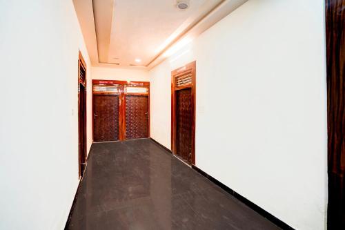 a corridor of a house with black floor and windows at Hotel O Parth Hotel And Restaurant in Fīrozābād