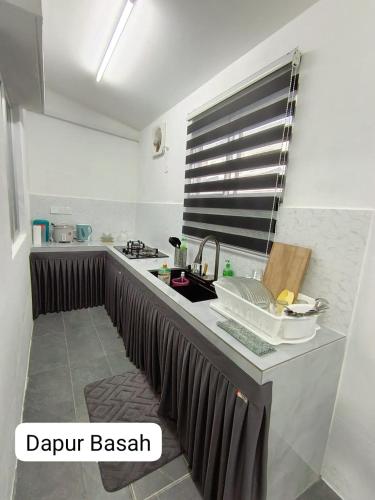 a kitchen with a sink and a counter top at Homestay AinulZahra in Seri Iskandar