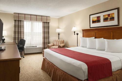 a hotel room with a large bed and a chair at Country Inn & Suites by Radisson, Rossford - Toledo South in Rossford