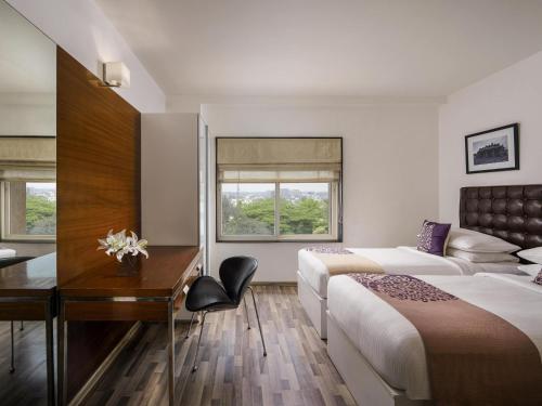 a hotel room with two beds and a desk at Grand Mercure Bangalore - An Accor Brand in Bengaluru