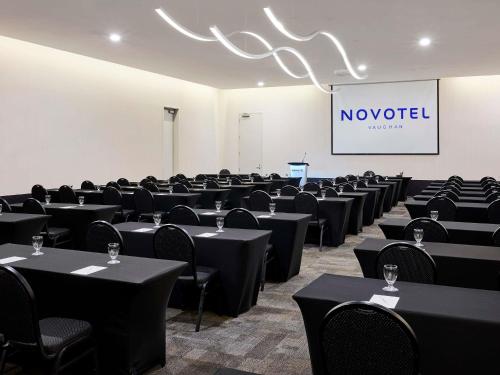 a conference room with tables and chairs and a screen at Novotel Toronto Vaughan Centre in Vaughan
