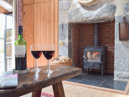 two glasses of wine on a table with a fireplace at The Byre in Saint Twynnells