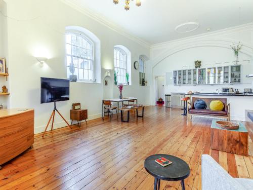 a living room with wooden floors and a flat screen tv at The Old School Room in Frome