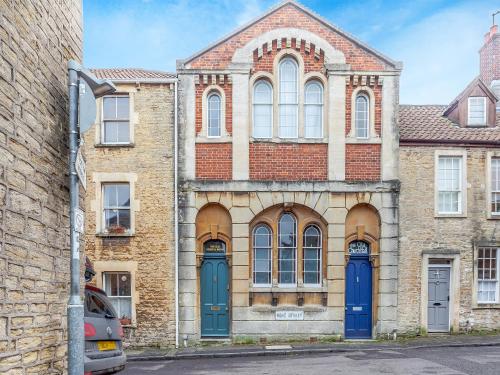an old brick building with blue doors on a street at The Old School Room in Frome