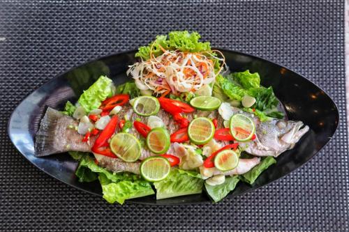 a plate with a salad with fish and vegetables at Twin Sands Resort Penthouse in Patong Beach