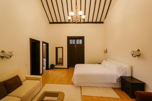 a bedroom with a bed and a couch and a chandelier at Hotel Rural Villa del Monte in Santa Brígida