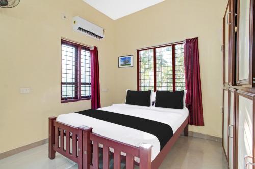 1 dormitorio con 1 cama grande y cortinas rojas en Hotel O Nakshathra Inn, en Kazhakuttam