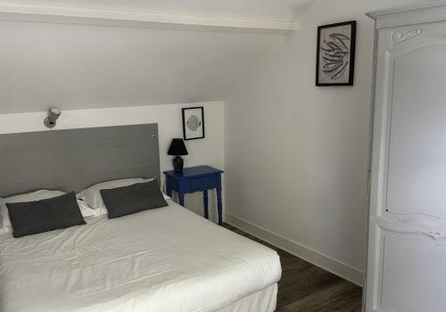 a bedroom with a white bed and a blue table at Logis Hôtel La Demeure du Perron in Quettehou