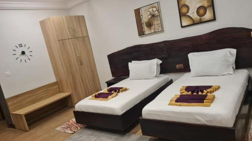 a bedroom with two beds and a clock on the wall at Sweet Garden Hotel Kumasi in Trofwi