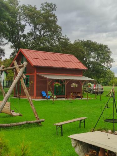 una piccola casa con tetto rosso e parco giochi di Domek letniskowy Słoneczny Zakątek a Frombork