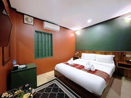 a bedroom with a large white bed with orange walls at Little Friendly Guest House with pool in Luang Prabang