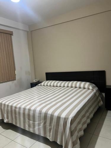 a bedroom with a bed with a striped blanket on it at Hotel Bamboo Sauces Morelia in Morelia