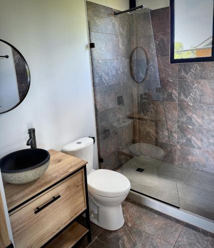 a bathroom with a toilet and a glass shower at Cabaña del lago con Jacuzzi in Rionegro