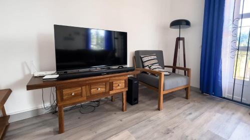 a living room with a flat screen tv and a chair at Surfers House - Garden & Views in La Gaulette