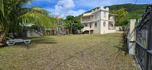 a large white house with a fence and a yard at Surfers House - Garden & Views in La Gaulette