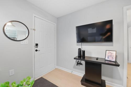 a living room with a flat screen tv on a white wall at Cozy Contemporary Stay I Pool & Gym I Free Parking in Spring Lake