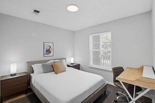 Un dormitorio blanco con una cama y un escritorio. en Fayetteville Bright & Chic Suite I Onsite Parking, en Spring Lake