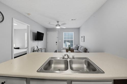 Una cocina con fregadero y una sala de estar. en Fayetteville Bright & Chic Suite I Onsite Parking, en Spring Lake