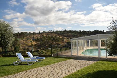 a pair of lounge chairs on the grass next to a pool at Villas Belita in Marco de Canaveses