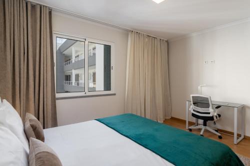 a bedroom with a bed and a desk and a chair at Madeira Ocean View Pool and Comfort in Caniço in Caniço