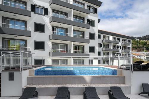 an apartment building with a swimming pool in front of it at Madeira Ocean View Pool and Comfort in Caniço in Caniço