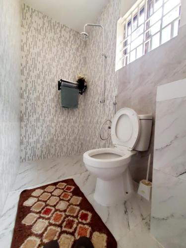 a bathroom with a toilet and a rug at Faraja Homestay Mwanza in Mwanza