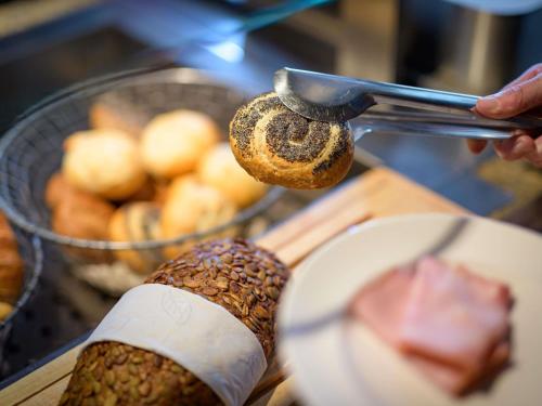 a person is holding up a bagel and a knife at ibis Stuttgart Airport Messe in Leinfelden-Echterdingen