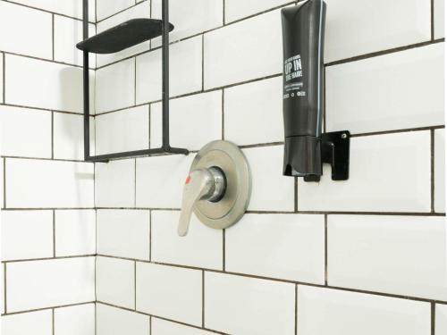 a shower head hanging on a white tiled wall at ibis Sao Luis in São Luís