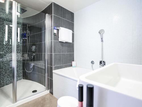 a bathroom with a shower and a tub and a sink at Novotel Suites Luxembourg in Luxembourg