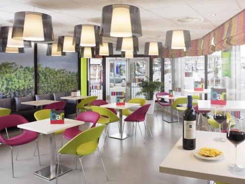 a restaurant with colorful chairs and tables and a bottle of wine at ibis Styles Bordeaux Saint Médard in Saint-Médard-en-Jalles