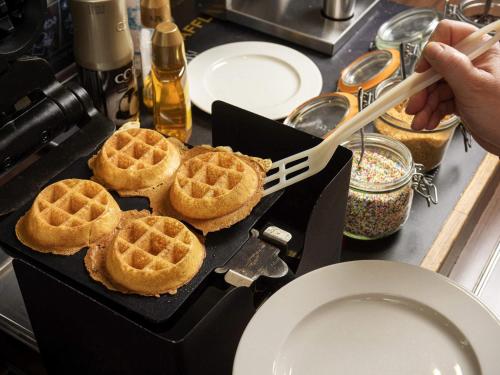 a person is cooking waffles on a grill with a spatula at ibis Sint Niklaas Centrum in Sint-Niklaas